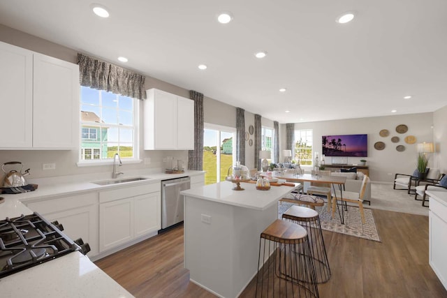 kitchen featuring white cabinets, dishwasher, light wood-type flooring, sink, and a center island