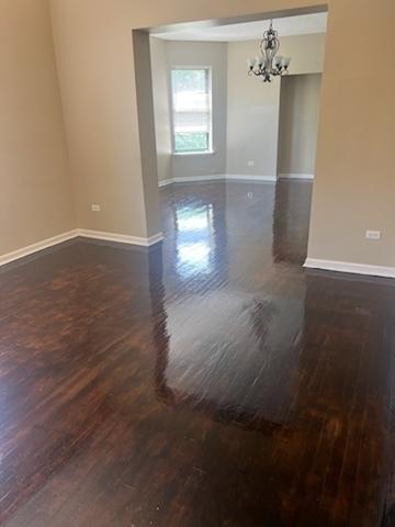 spare room featuring a chandelier and dark hardwood / wood-style floors