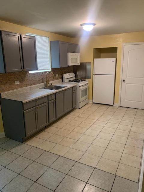 kitchen featuring backsplash, gray cabinetry, white appliances, sink, and light tile patterned floors