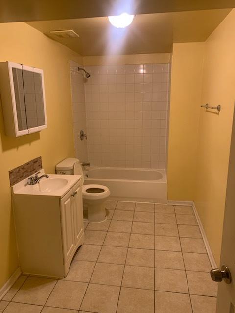 full bathroom with toilet, vanity, tile patterned floors, and tiled shower / bath combo