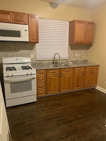 kitchen with tasteful backsplash, white appliances, sink, and dark wood-type flooring