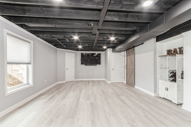 basement with light wood-type flooring and a barn door