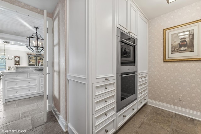 kitchen featuring white cabinetry, double oven, hanging light fixtures, and an inviting chandelier