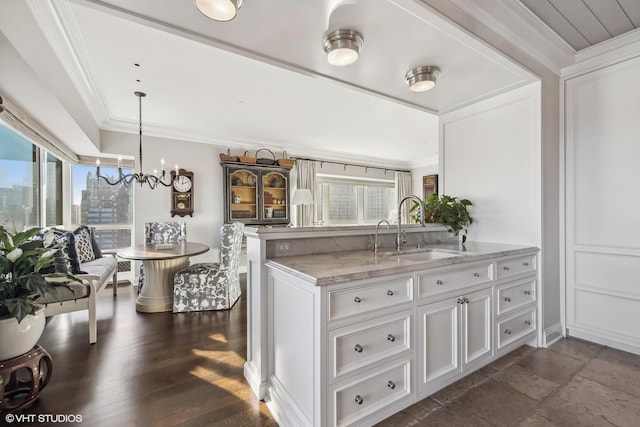 kitchen with white cabinetry, plenty of natural light, sink, and crown molding