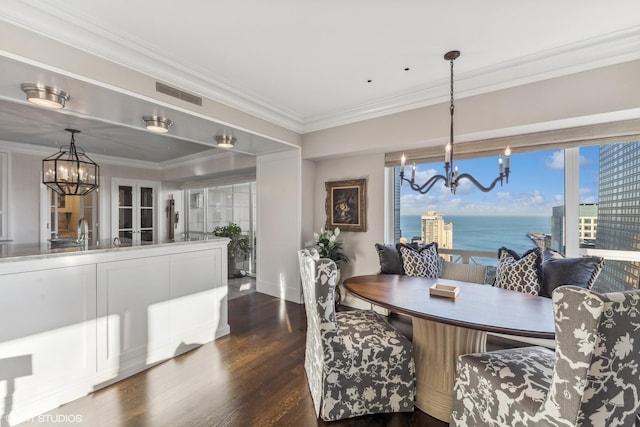 dining space featuring a water view, dark hardwood / wood-style floors, crown molding, and a chandelier