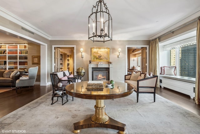 living area featuring hardwood / wood-style flooring, ornamental molding, and a notable chandelier