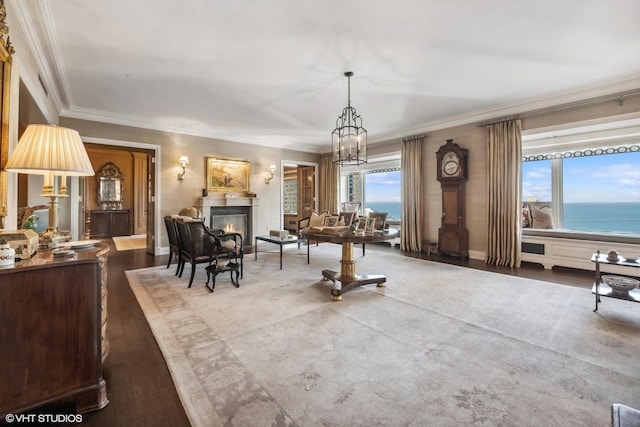 dining space with wood-type flooring, ornamental molding, a chandelier, and a water view