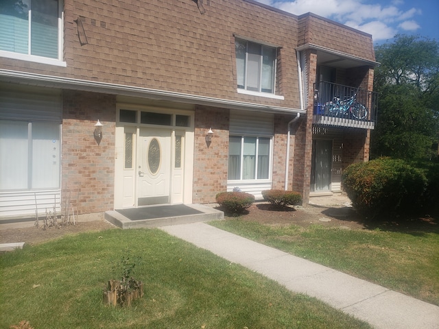 view of front of property featuring a front yard and a balcony