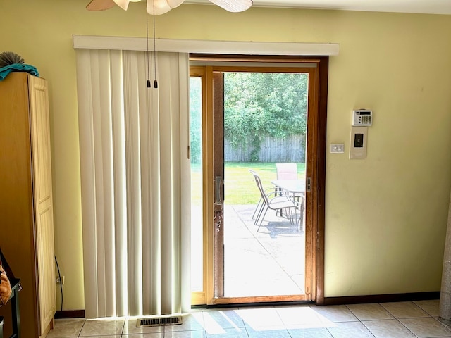 doorway with light tile patterned floors, ceiling fan, and a wealth of natural light