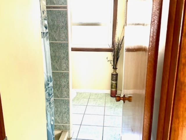 bathroom with curtained shower and tile patterned flooring