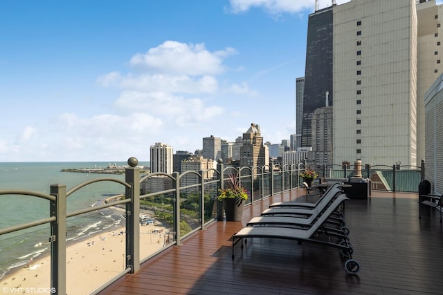 wooden terrace featuring a water view, a view of city, and a view of the beach