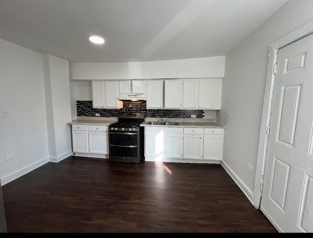 kitchen with under cabinet range hood, backsplash, dark wood finished floors, light countertops, and range with two ovens