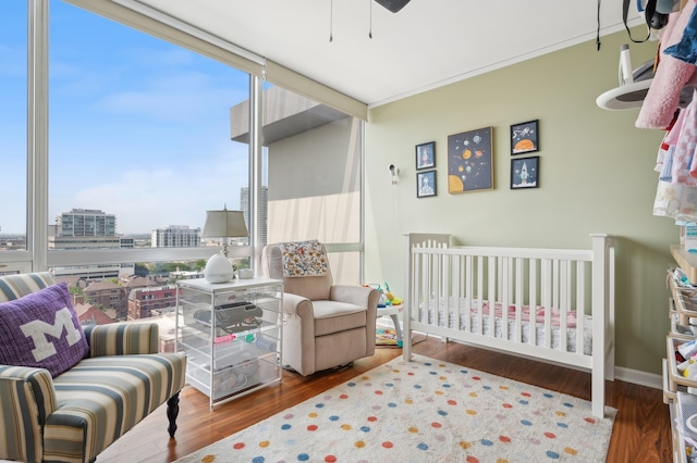 bedroom featuring a wall of windows, dark wood-type flooring, multiple windows, and a nursery area