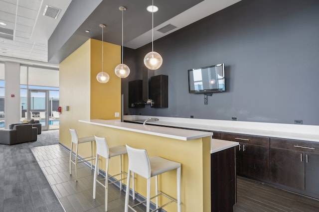 kitchen featuring dark brown cabinetry, a breakfast bar area, and decorative light fixtures