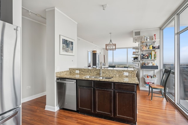 kitchen featuring appliances with stainless steel finishes, floor to ceiling windows, hardwood / wood-style flooring, and light stone counters