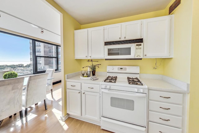 kitchen featuring white appliances, light wood-type flooring, and white cabinetry