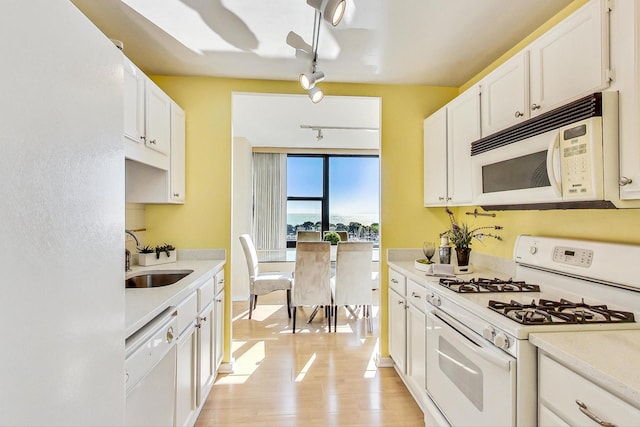 kitchen with white appliances, track lighting, white cabinets, light hardwood / wood-style flooring, and sink