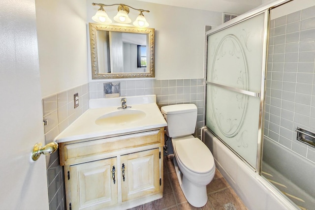 full bathroom featuring toilet, tile walls, tile patterned floors, vanity, and combined bath / shower with glass door