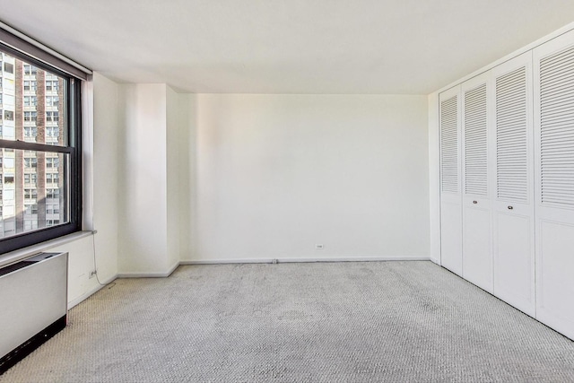 unfurnished bedroom featuring radiator heating unit, a closet, and light colored carpet