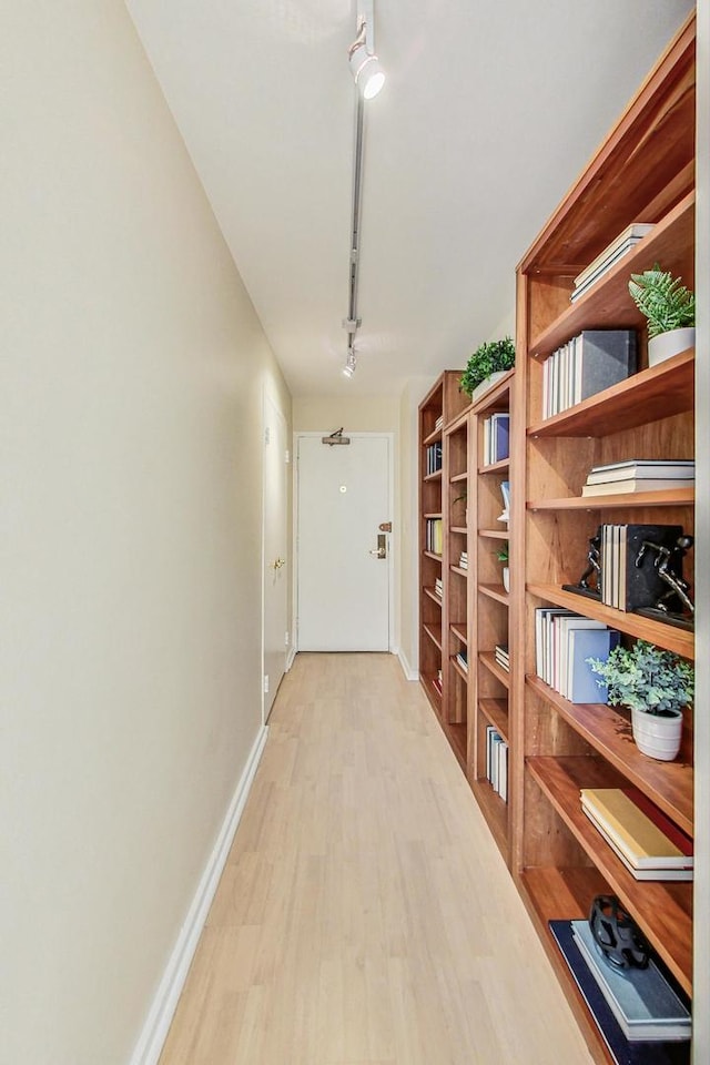 corridor with light hardwood / wood-style flooring and track lighting