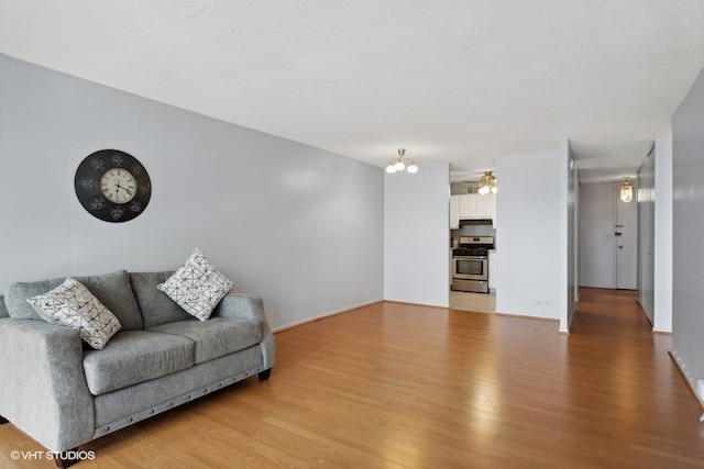 living room with light hardwood / wood-style flooring and ceiling fan with notable chandelier