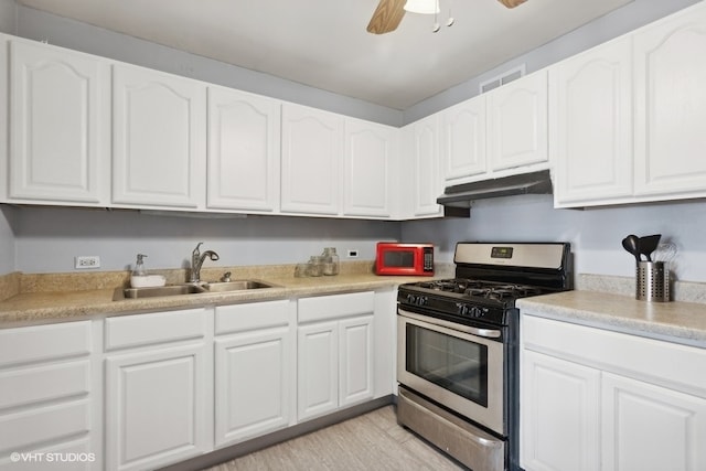 kitchen featuring stainless steel gas range oven, white cabinets, light wood-type flooring, ceiling fan, and sink