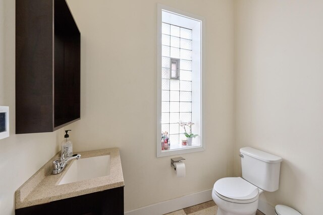 bathroom with tile patterned flooring, vanity, toilet, and plenty of natural light