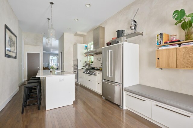 kitchen featuring stainless steel appliances, white cabinets, hanging light fixtures, a breakfast bar area, and an island with sink