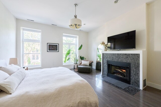 bedroom featuring a tile fireplace and dark wood-type flooring