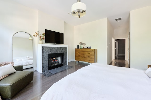 bedroom with a tile fireplace and dark hardwood / wood-style floors