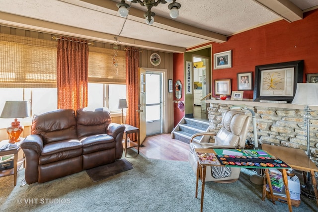 living room featuring beamed ceiling, carpet, and a textured ceiling