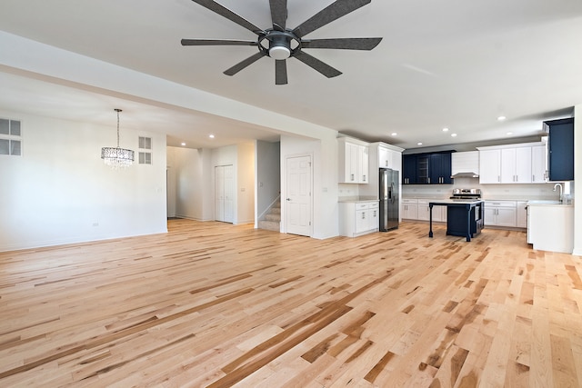 unfurnished living room featuring ceiling fan, light hardwood / wood-style floors, and sink