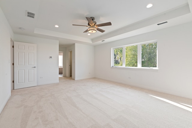 carpeted empty room featuring a tray ceiling and ceiling fan