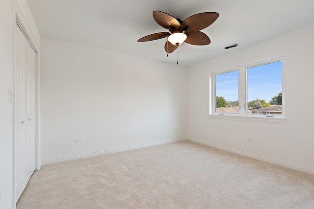 unfurnished bedroom featuring light colored carpet, ceiling fan, and a closet