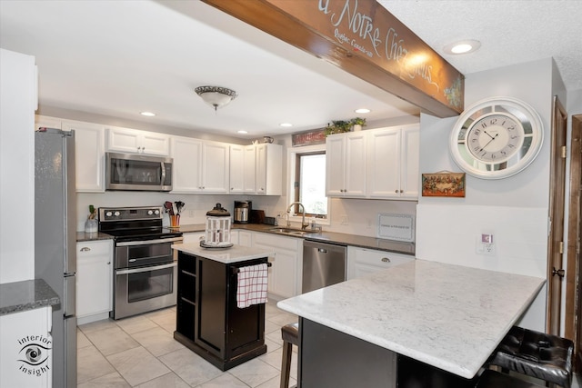 kitchen featuring a center island, sink, a kitchen breakfast bar, appliances with stainless steel finishes, and light stone countertops