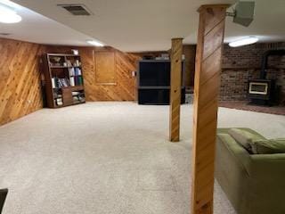 basement with a wood stove, carpet, and wooden walls