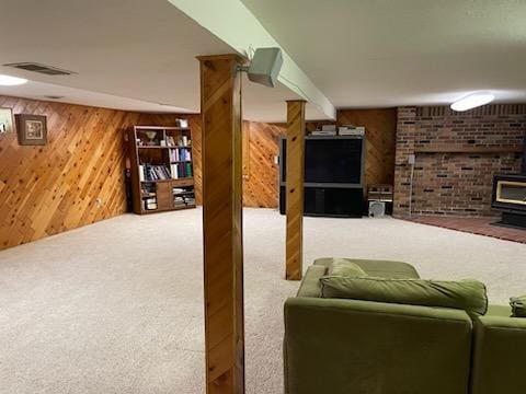 living room with a wood stove, wood walls, and carpet flooring