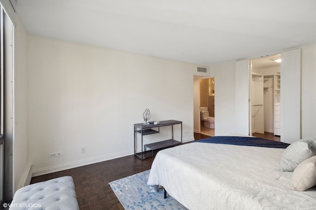 bedroom with ensuite bathroom, a closet, a walk in closet, and dark parquet floors