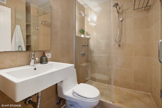 bathroom with tile walls, a shower with door, toilet, and sink