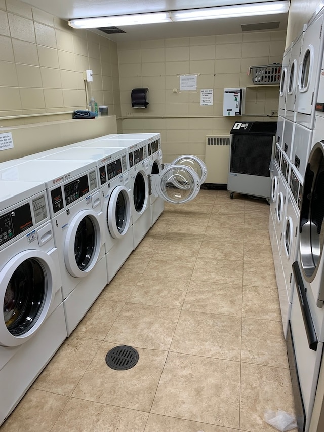 laundry room featuring radiator, independent washer and dryer, light tile patterned floors, and stacked washer / drying machine