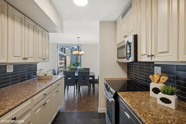 kitchen featuring stove, dark parquet floors, decorative backsplash, stone counters, and a chandelier