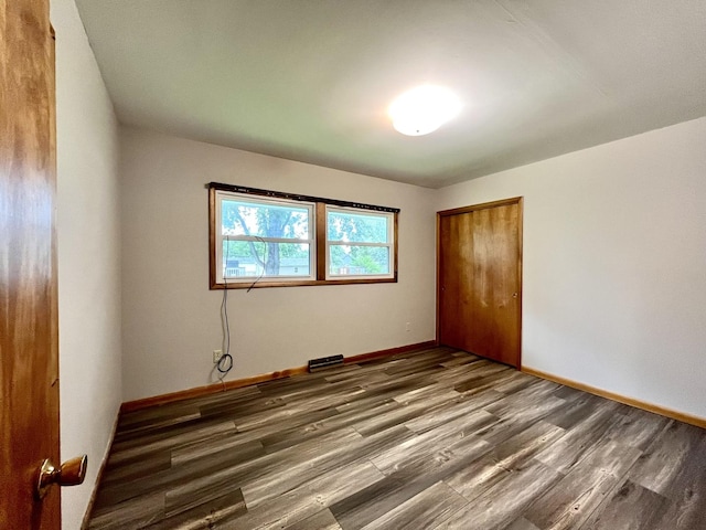 unfurnished bedroom with dark hardwood / wood-style floors and a closet