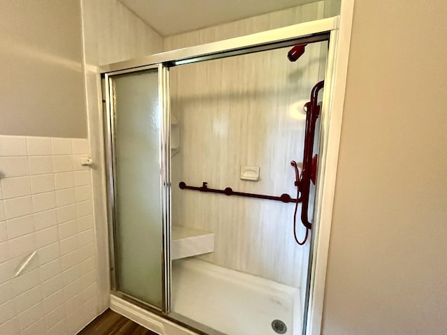 bathroom with an enclosed shower, tile walls, and hardwood / wood-style flooring