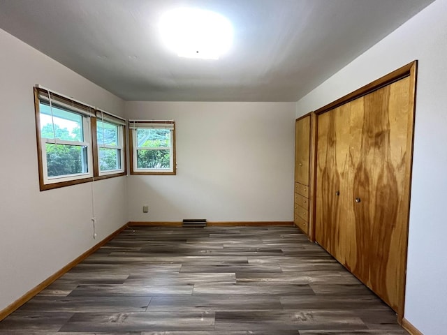 unfurnished bedroom featuring dark hardwood / wood-style flooring and a closet