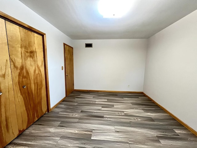 unfurnished bedroom featuring a closet and dark wood-type flooring