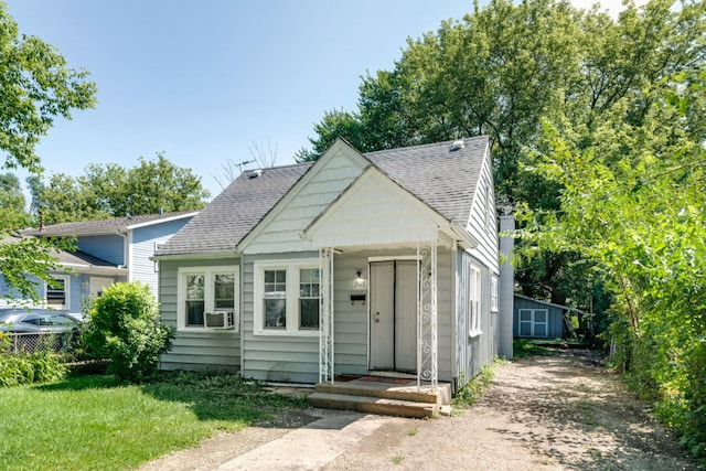 bungalow-style house featuring cooling unit and a front lawn