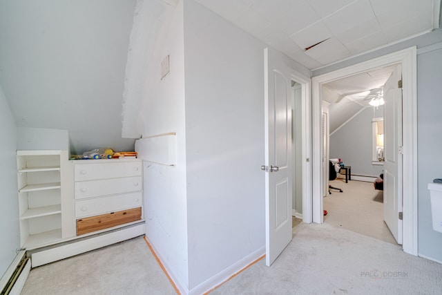 hallway with lofted ceiling, a baseboard heating unit, and light colored carpet