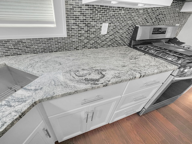 room details with white cabinetry, light stone countertops, dark wood-type flooring, and tasteful backsplash