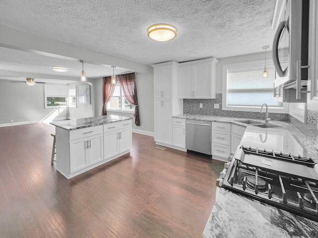 kitchen with light stone counters, white cabinets, appliances with stainless steel finishes, and sink