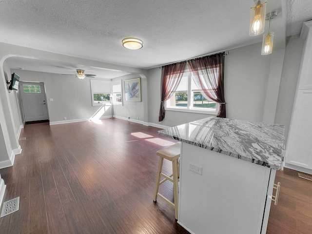 unfurnished living room featuring ceiling fan, a textured ceiling, and dark wood-type flooring